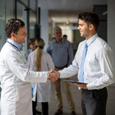A doctor and healthcare administrator shake hands