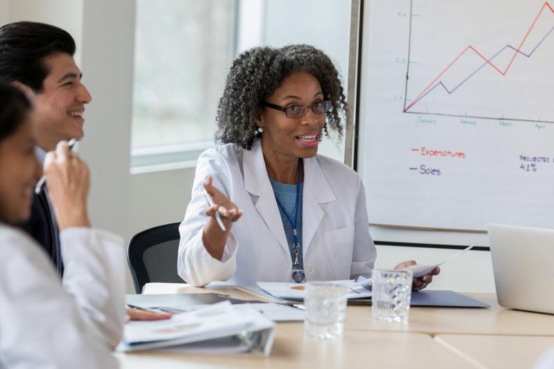 A female healthcare executive confers with her colleagues in a meeting