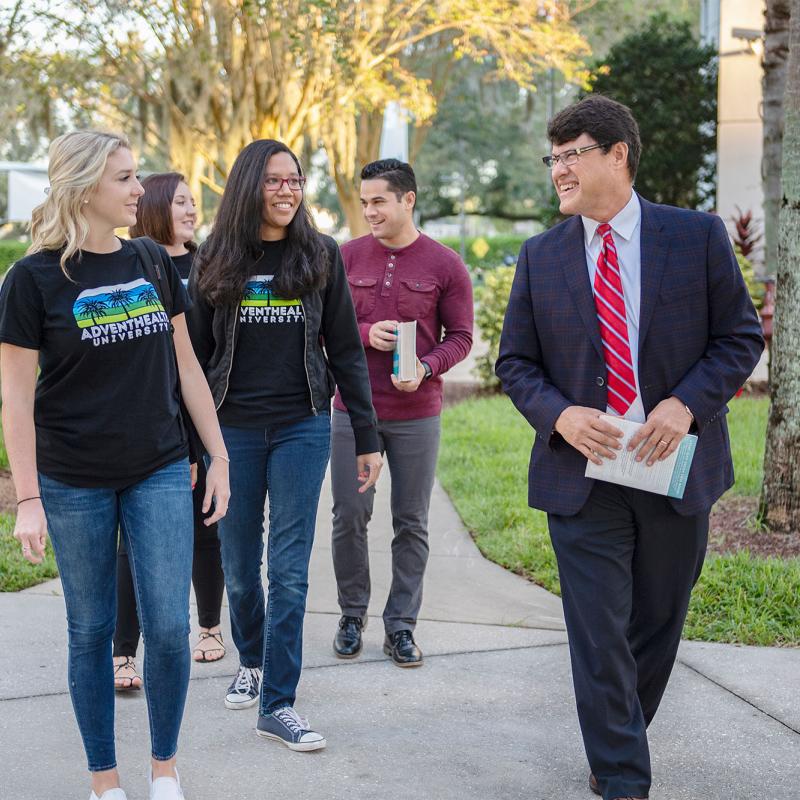 A group of students walking outdoors with the university president